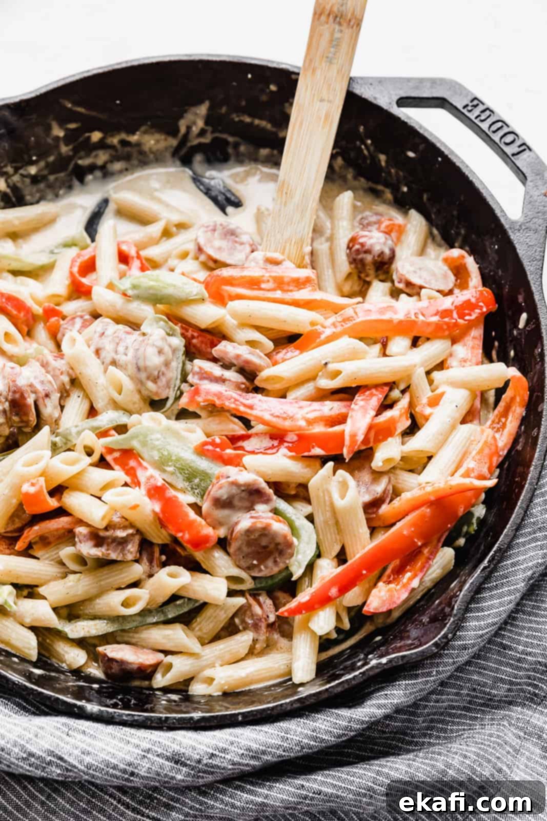 Spicy Cajun Sausage Pasta 10 A vibrant close-up of creamy Cajun Sausage Pasta, featuring perfectly cooked pasta, colorful bell peppers, and smoky Andouille sausage, all coated in a rich, savory sauce, presented in a black skillet.