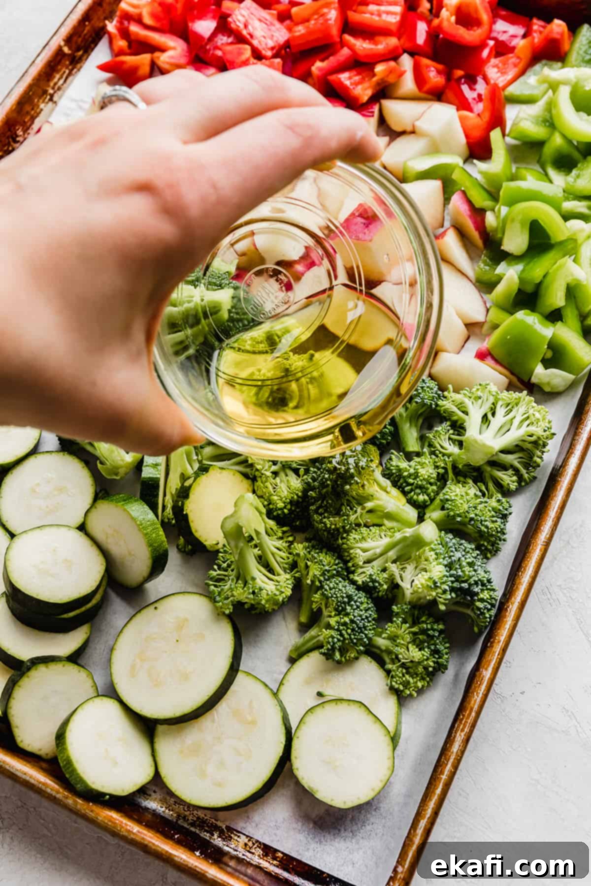 One Pan Roasted Italian Sausage and Vibrant Vegetables 5 Olive oil being poured over Sheet Pan Sausage and Veggies.