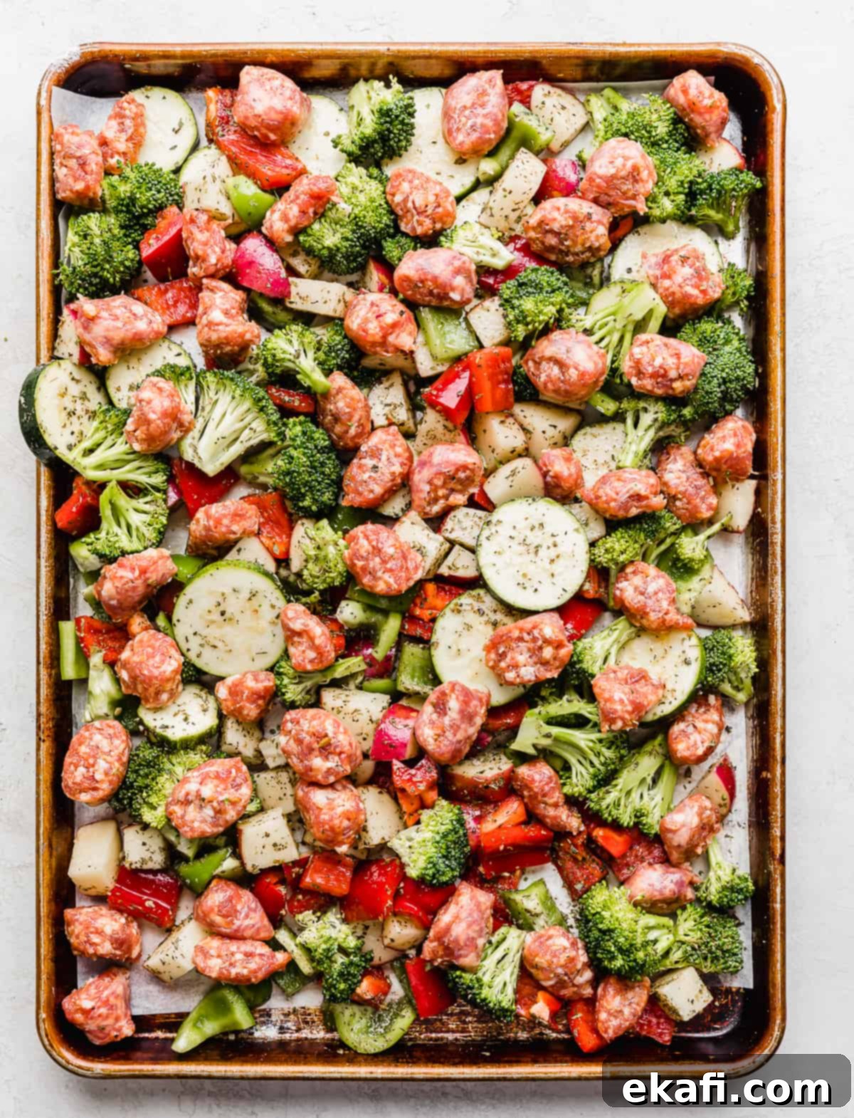 One Pan Roasted Italian Sausage and Vibrant Vegetables 6 Unbaked Italian sausage and chopped veggies on a baking sheet.