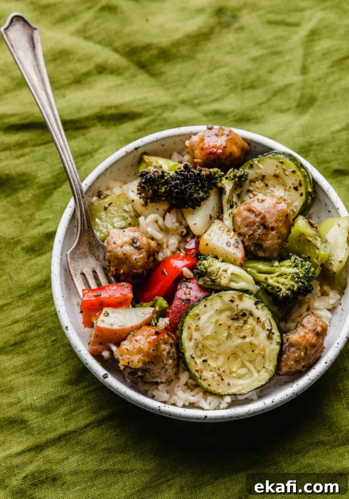 One Pan Roasted Italian Sausage and Vibrant Vegetables 9 A white plate full of Sheet Pan Sausage and Veggies, on a green linen napkin.