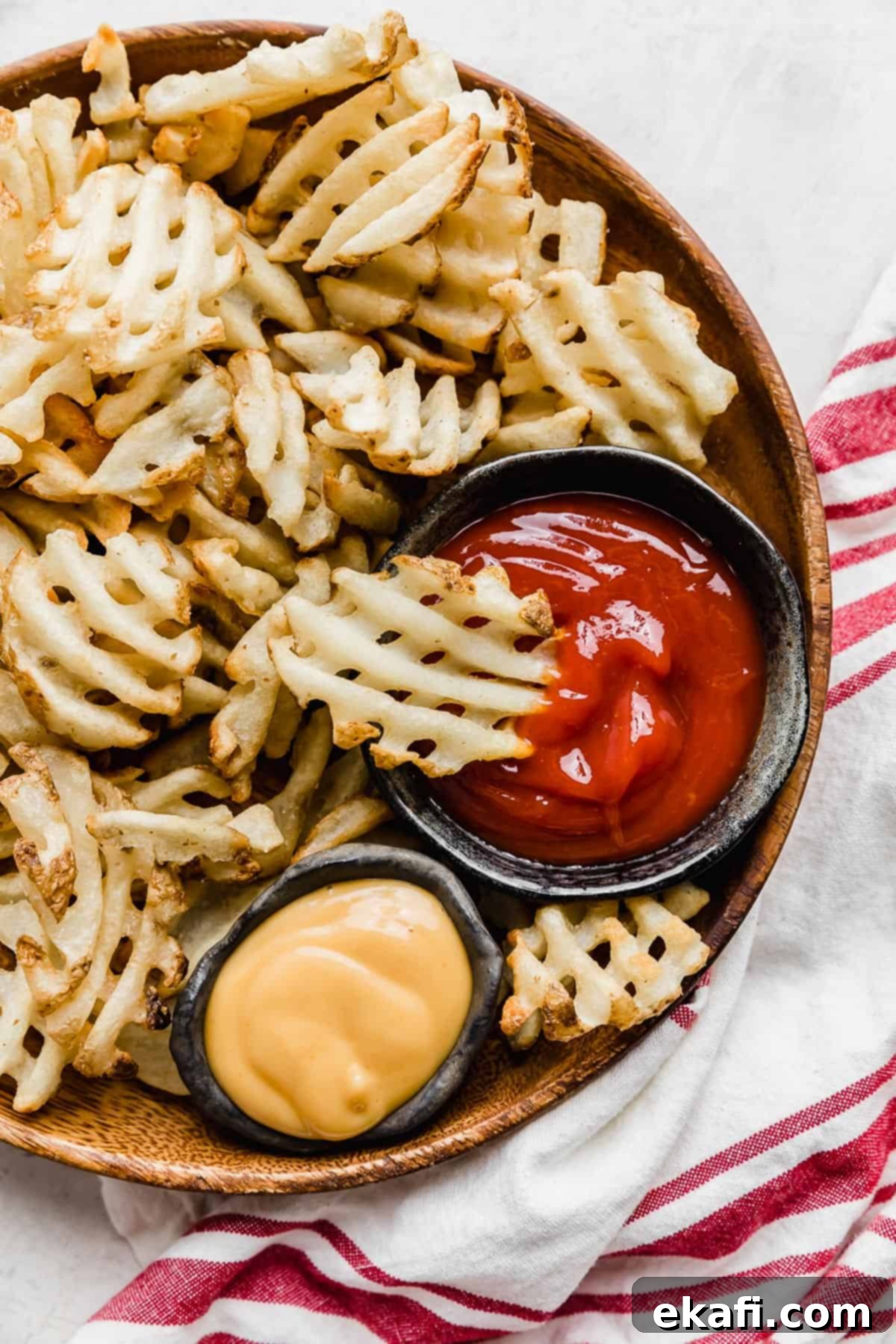 Πατάτες Waffle στη Φριτέζα Αέρος 2 Τραγανές πατάτες βάφλα μαγειρεμένες σε φριτέζα αέρος, σερβιρισμένες σε πιάτο με σάλτσες.