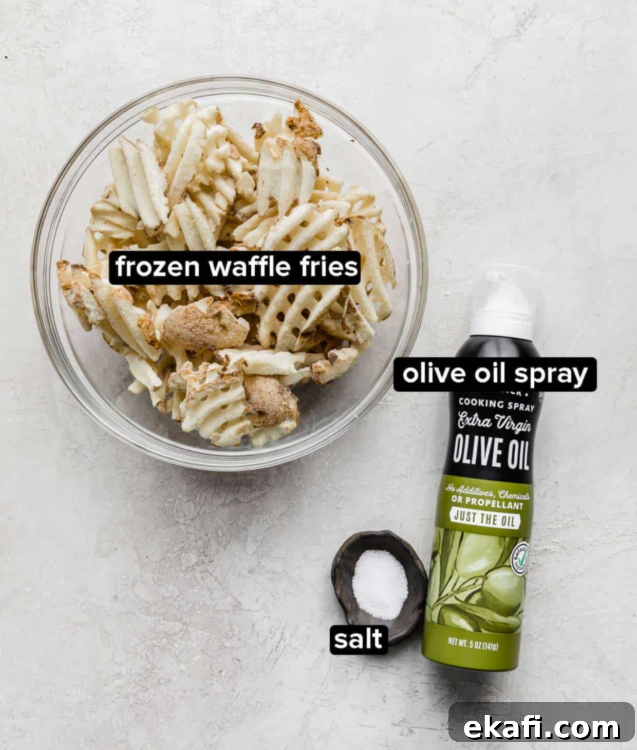 Πατάτες Waffle στη Φριτέζα Αέρος 3 Κατεψυγμένες πατάτες βάφλα σε γυάλινο μπολ με ένα μπολ αλάτι και σπρέι ελαιολάδου δίπλα στο μπολ, έτοιμα για μαγείρεμα.
