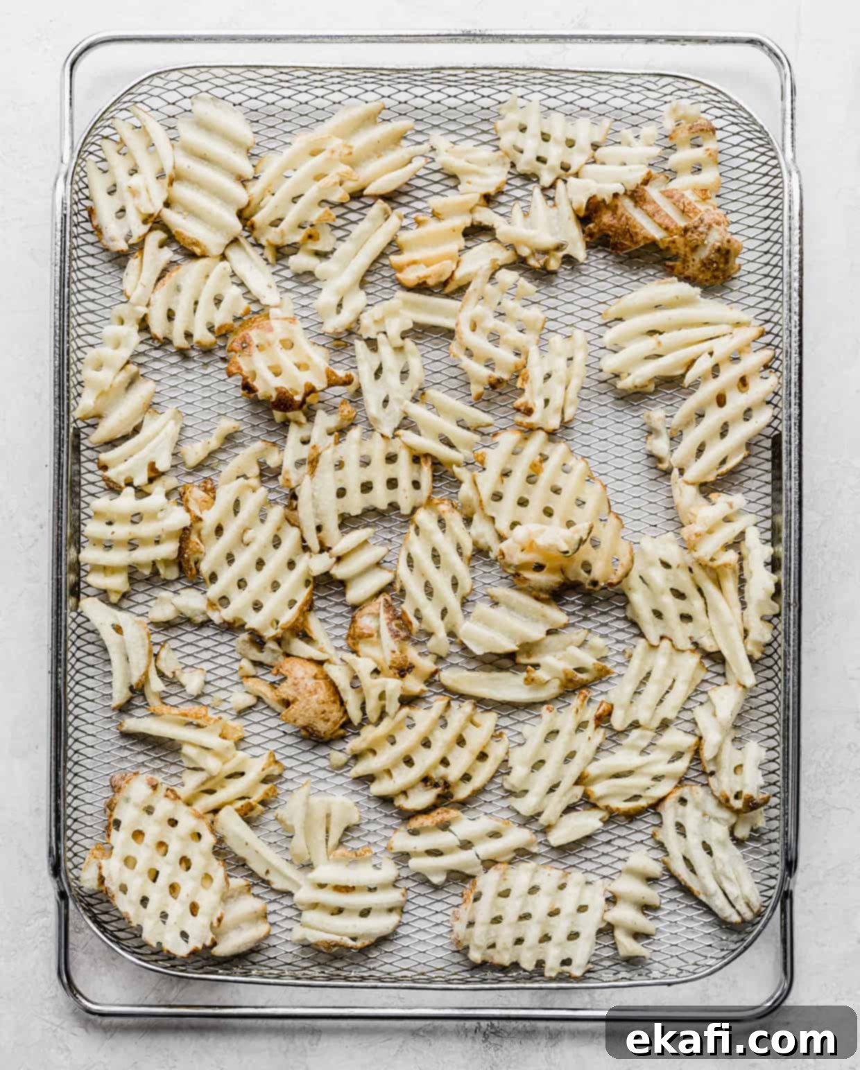 Πατάτες Waffle στη Φριτέζα Αέρος 4 Μια συρμάτινη σχάρα φριτέζας αέρος με κατεψυγμένες πατάτες βάφλα απλωμένες ομοιόμορφα πάνω της.