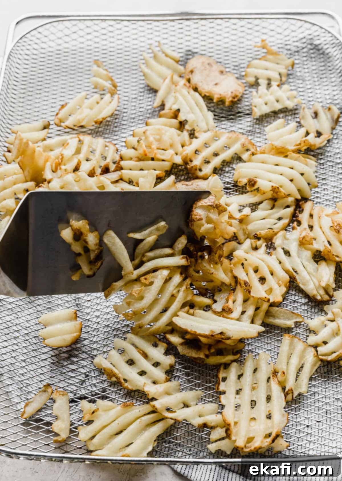 Πατάτες Waffle στη Φριτέζα Αέρος 5 Πατάτες βάφλα που μαγειρεύονται σε φριτέζα αέρος, αποκτώντας ένα ελαφρύ χρυσό χρώμα και τραγανή υφή.