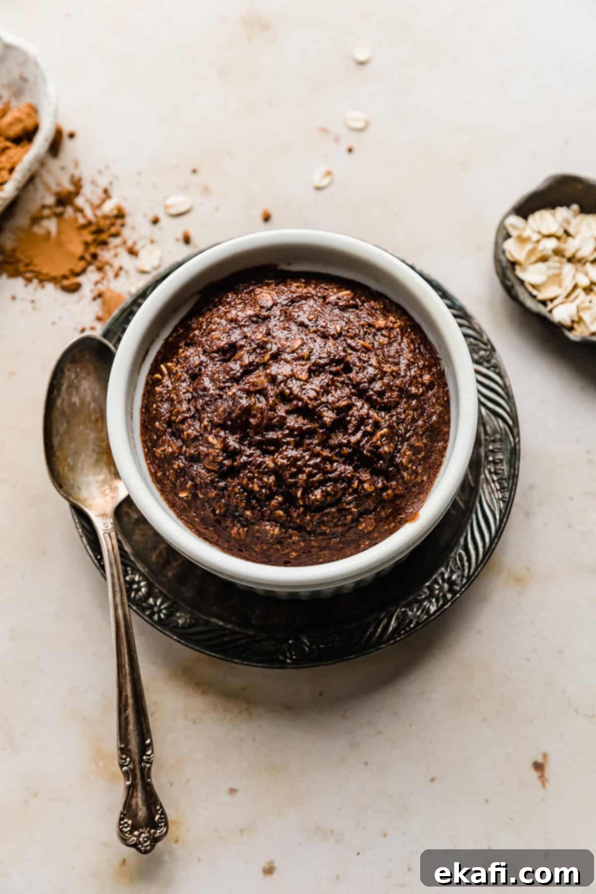 Chocolate Baked Oats Perfection 2 Chocolate Baked Oats in a white ramekin on a brown plate.