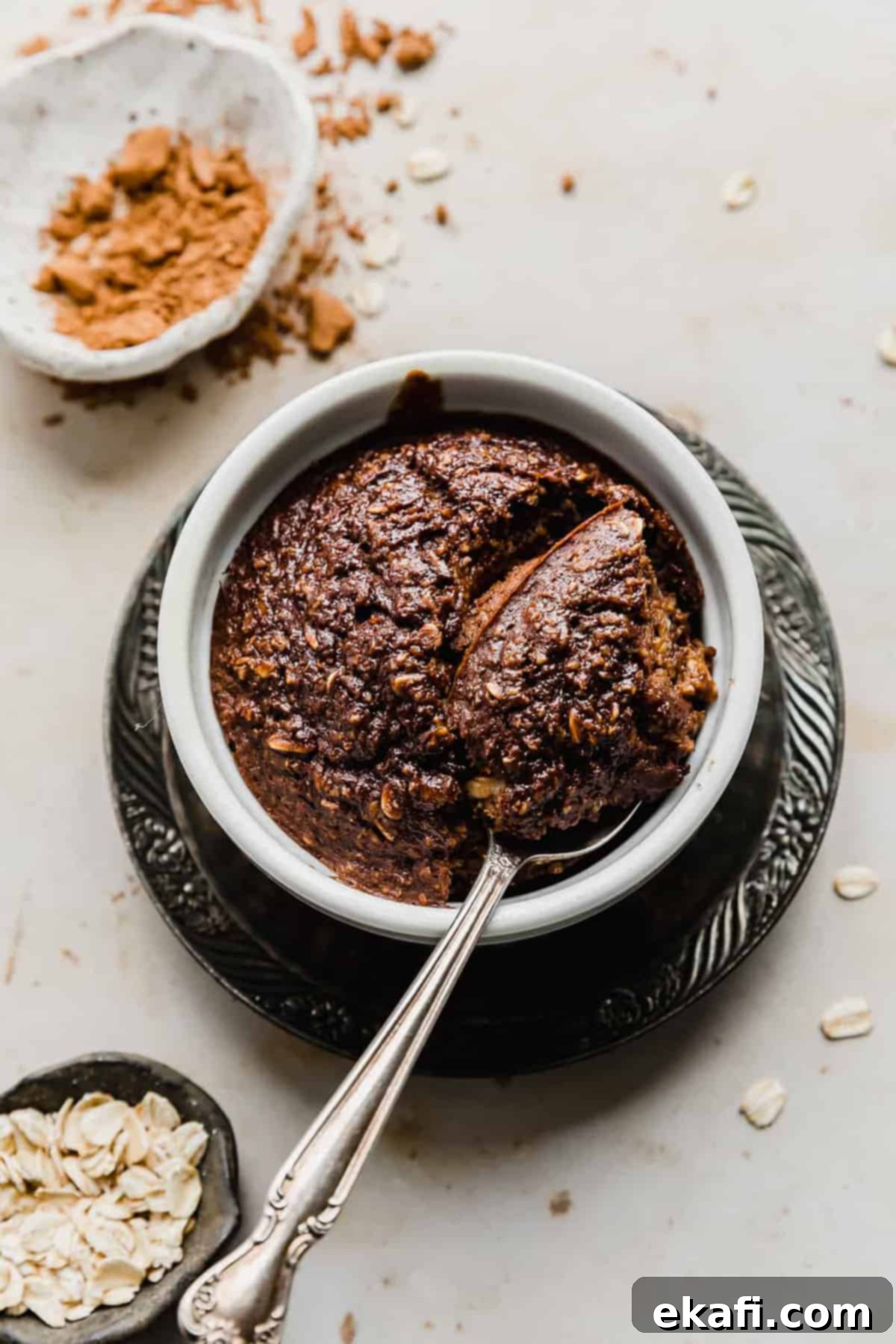 Chocolate Baked Oats Perfection 7 Chocolate Baked Oats in a white ramekin with a spoon scooping out some oats.