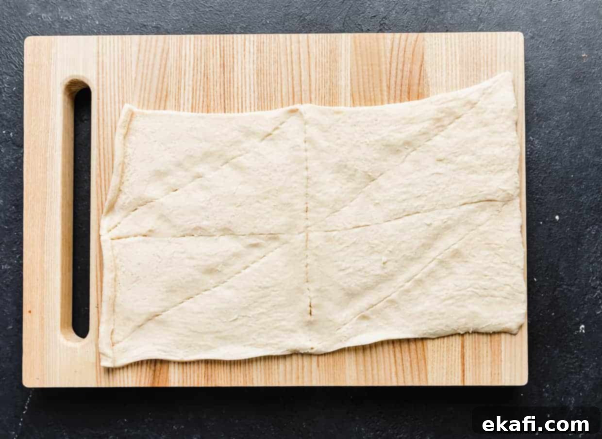 Mummy Hot Dogs 4 A wooden cutting board with an unrolled crescent roll sheet on it.