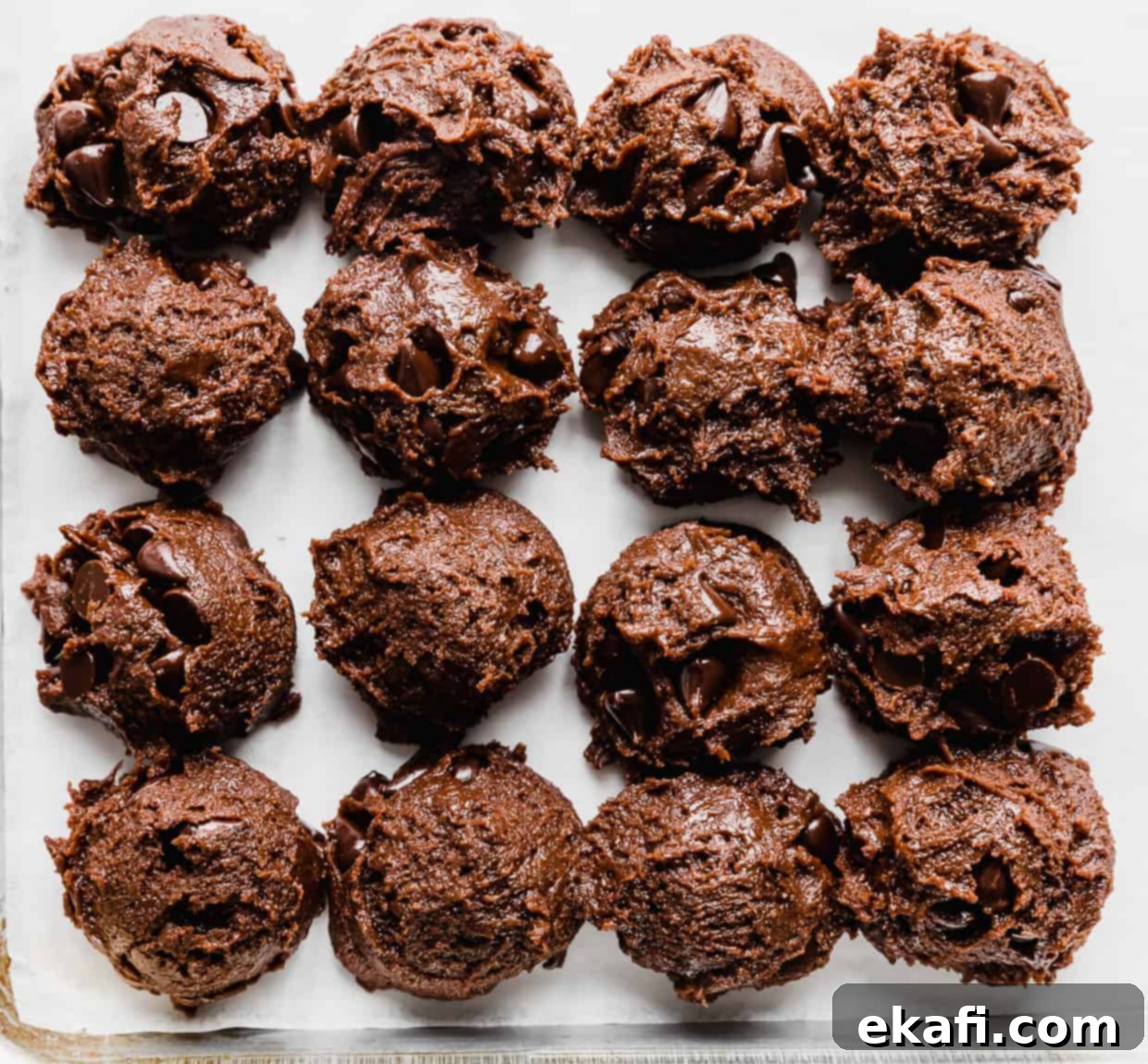 Decadent Double Chocolate Bites 12 Neatly scooped double chocolate chip cookie dough balls lined up on a baking sheet, ready for the oven.
