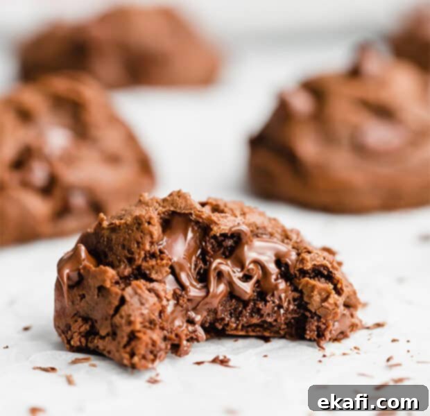 Decadent Double Chocolate Bites 14 A close up photo of a soft, melty double chocolate chip cookie with a bite taken out, showing the fudgy interior and chocolate chips.