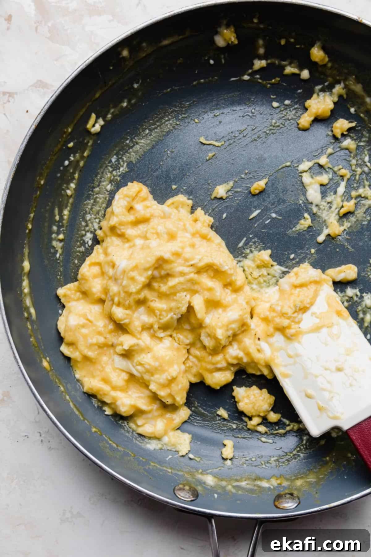Golden Cheese Scramble 8 A close-up of perfectly cooked, fluffy cheesy scrambled eggs resting in a gray nonstick skillet, ready to be served.