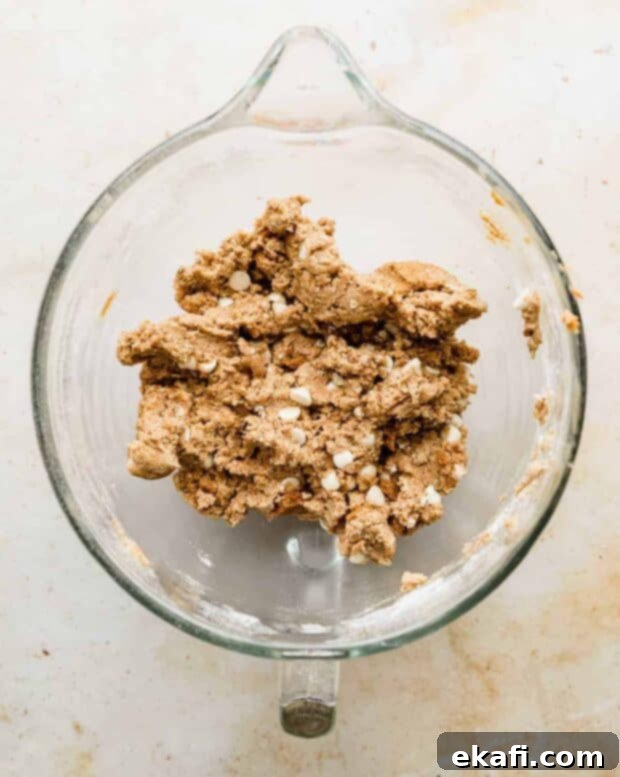 Crumbl's Dreamy Biscoff White Chocolate Cookies 4 Cookie dough balls flattened on a baking sheet, ready for the oven.