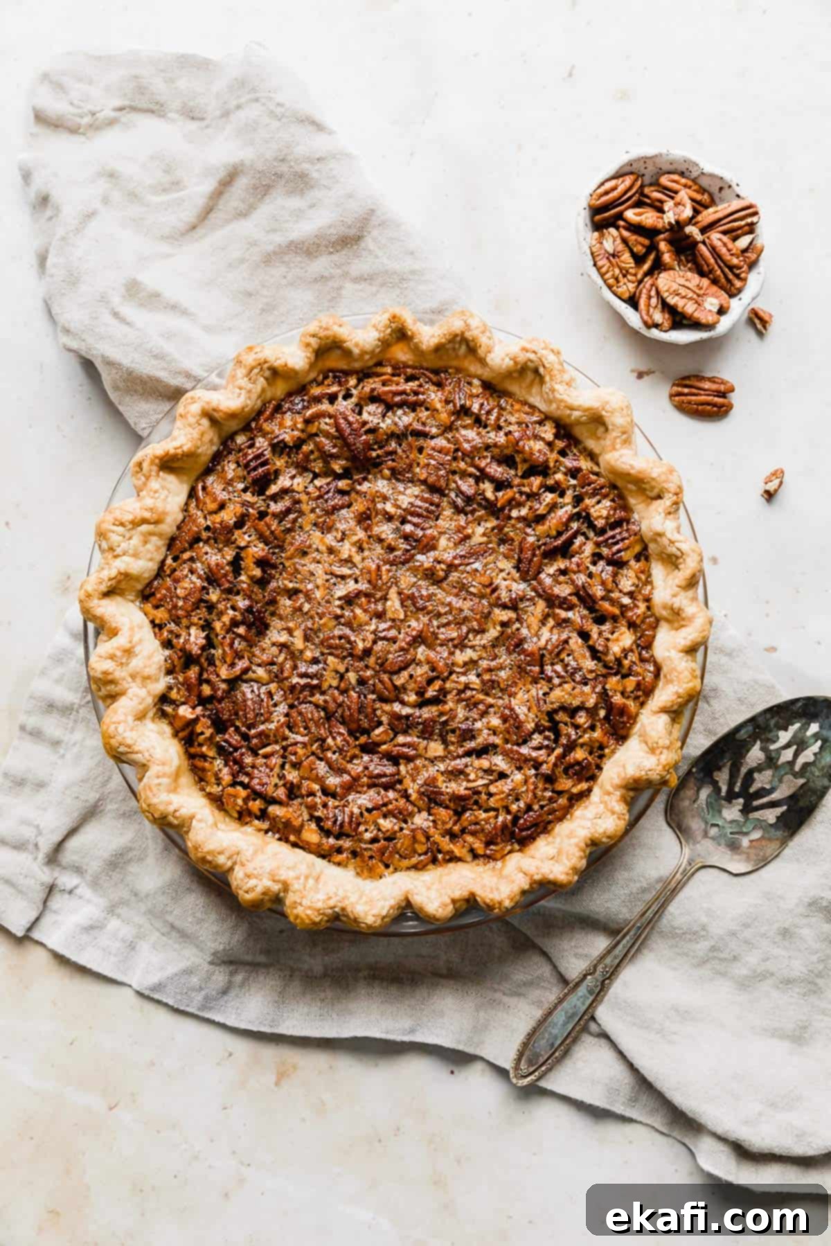 Sweet Southern Comfort: The Perfect Pecan Pie 8 A beautifully baked Southern Pecan Pie resting on a textured tan linen, showing off its golden crust and glossy, pecan-covered top.