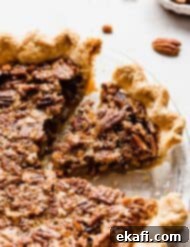 Sweet Southern Comfort: The Perfect Pecan Pie 10 A beautifully baked pecan pie on a white background, with scattered pecan pieces, highlighting the golden crust and rich topping.