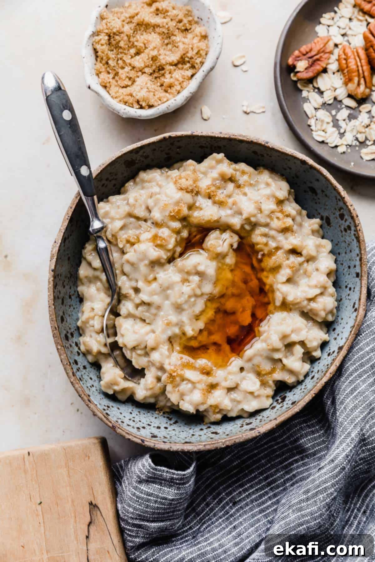 Golden Maple Brown Sugar Oats 7 A bowl of Maple and Brown Sugar Oatmeal on a cream background with a bowl of pecans and brown sugar to the side.