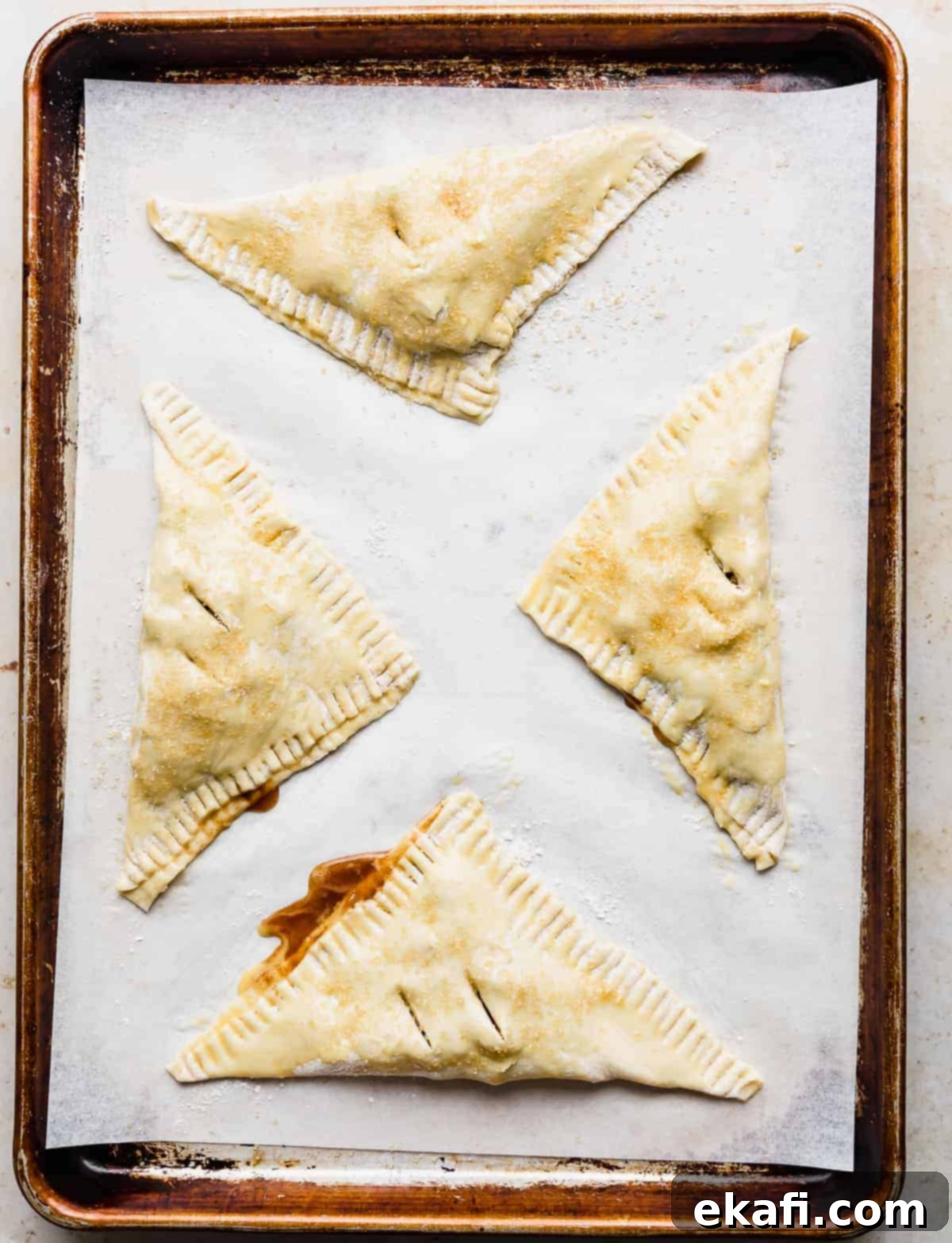 Flaky Apple Turnovers 11 Unbaked Puff Pastry Apple Turnovers on a parchment lined baking sheet.