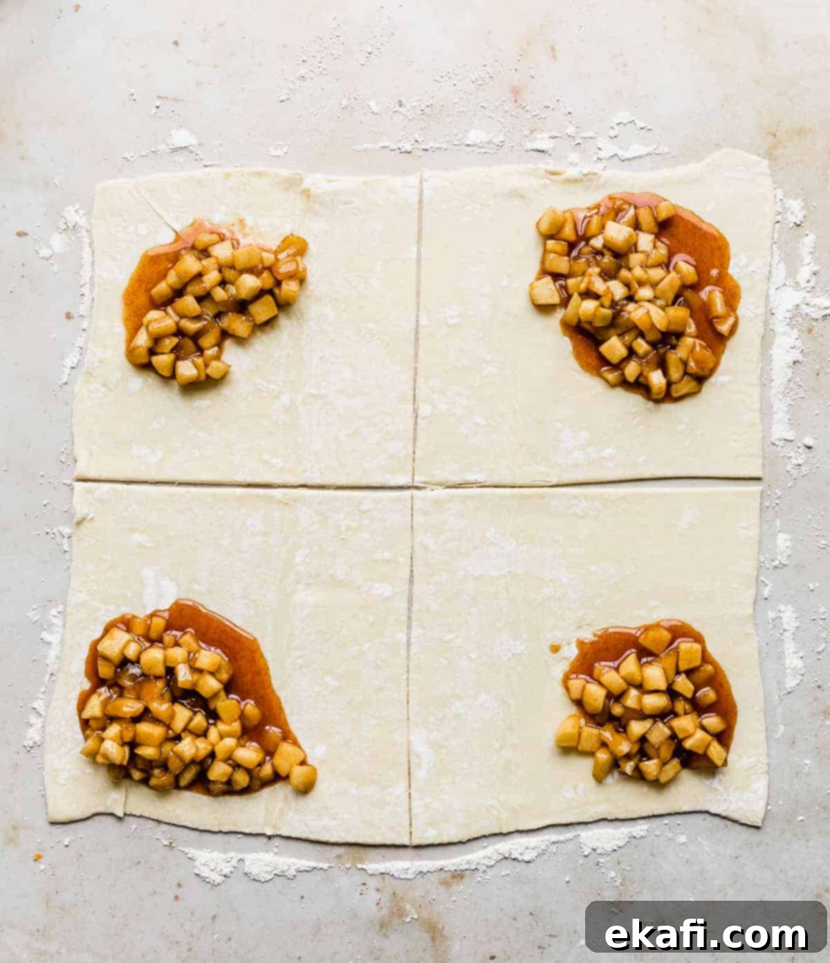 Flaky Apple Turnovers 9 Squares of puff pastry topped with a brown diced apple mixture in one corner of each square.