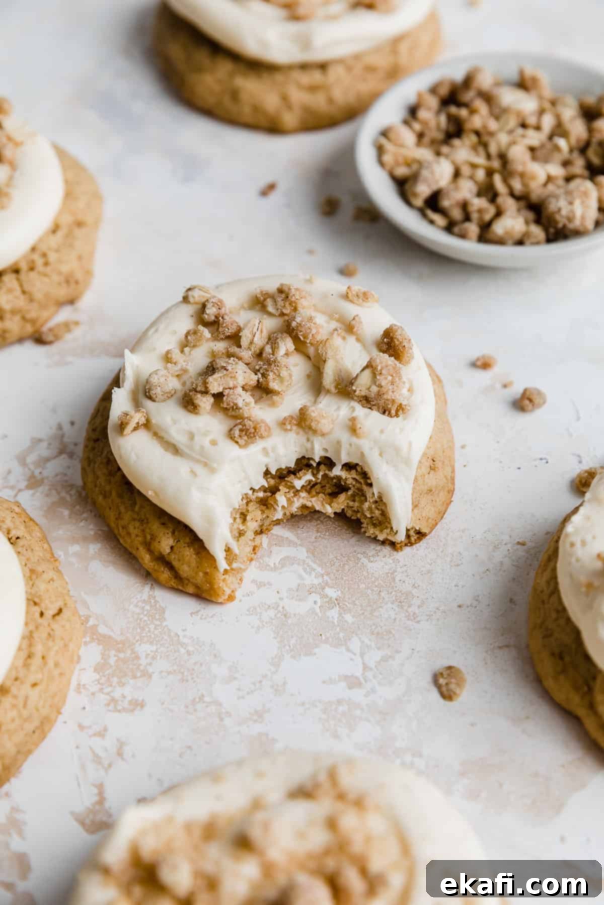 Gooey Caramel Apple Cookies 3 A bite taken out of a caramel apple flavored cookie that's topped with a caramel frosting and homemade streusel.