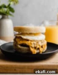 From Scratch Sausage and Egg Breakfast Sandwich 12 Homemade Sausage and Egg McMuffin on a black plate with orange juice in the background.