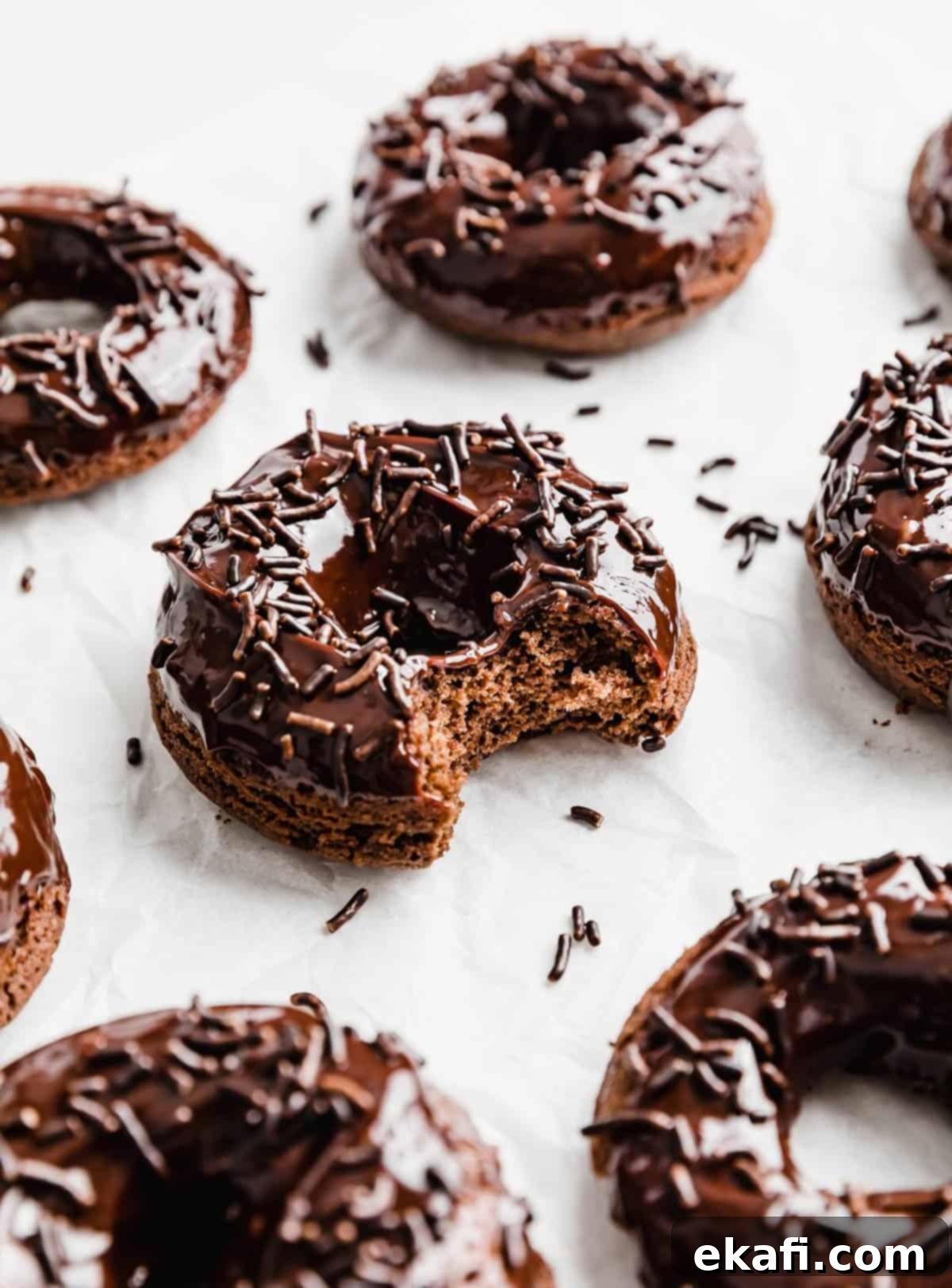 Ultimate Chocolate Donuts 14 A close-up of a delectable Baked Chocolate Doughnut, adorned with chocolate sprinkles and showing a bite taken out, highlighting its moist interior.