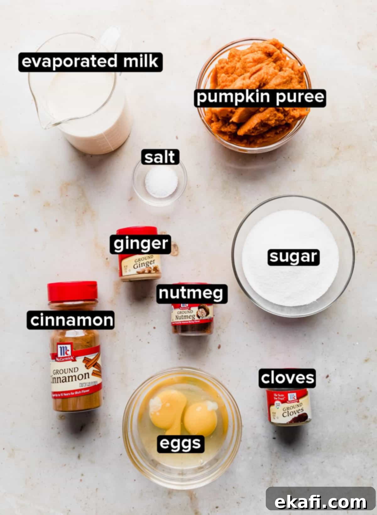 Pure Pumpkin Custard 3 A rustic shot of all the Crustless Pumpkin Pie ingredients neatly laid out on a cream marbled background, ready for baking.