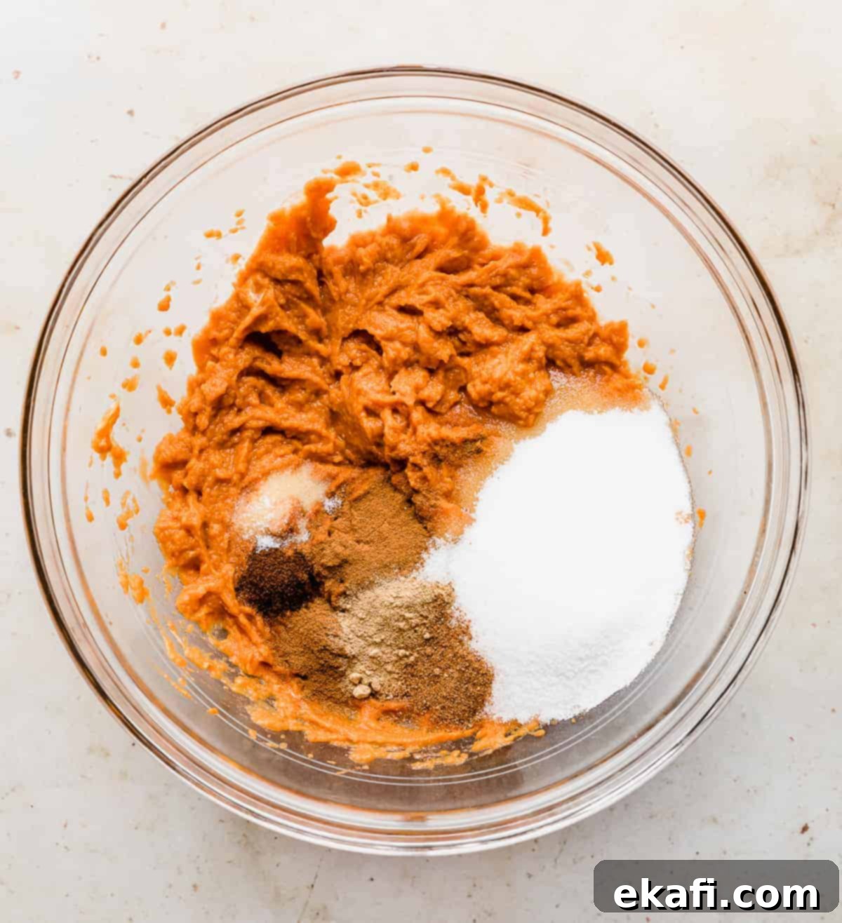 Pure Pumpkin Custard 5 Various Crustless Pumpkin Pie ingredients, including sugar and spices, waiting to be fully mixed into the creamy pumpkin base in a glass bowl.