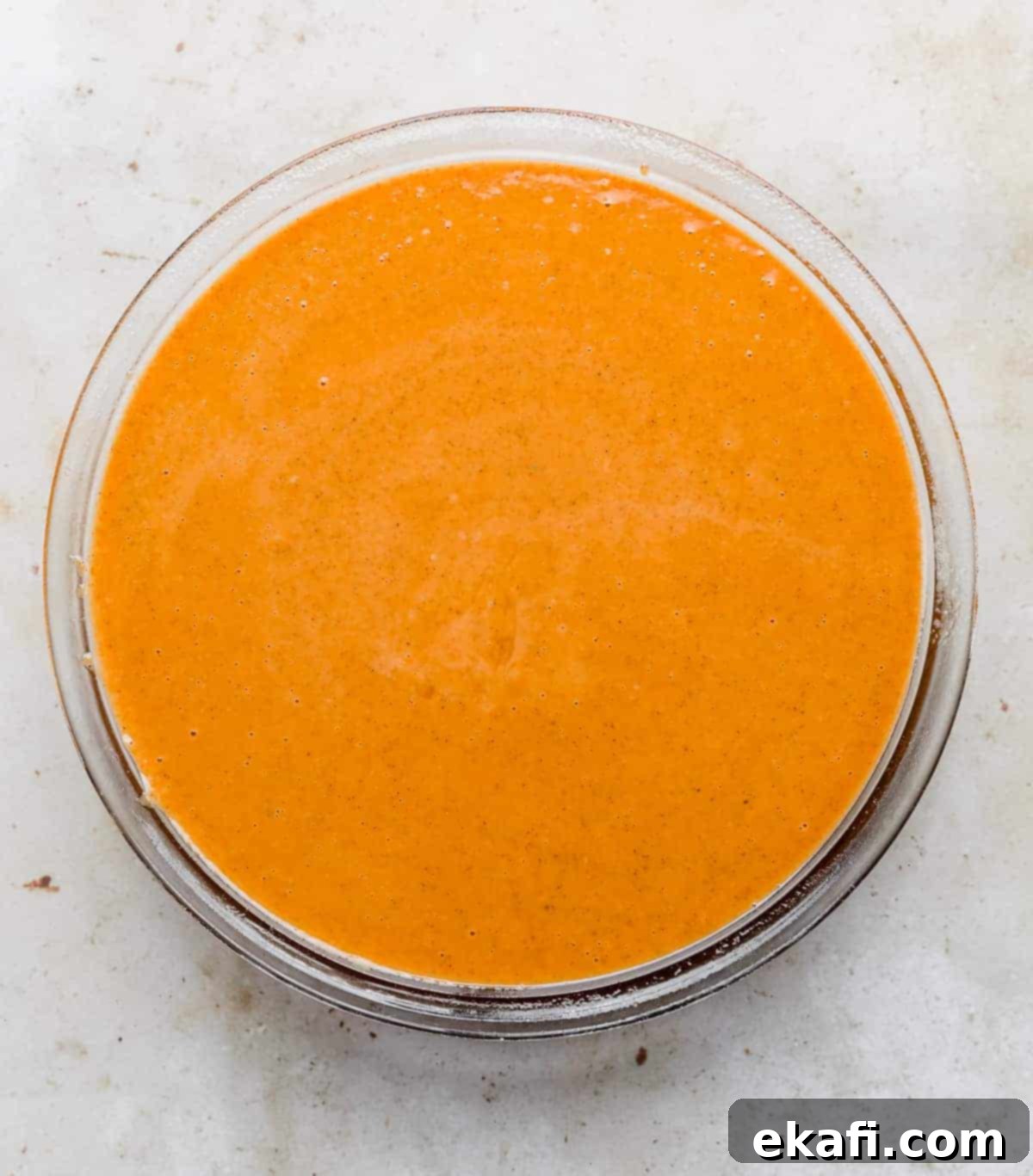 Pure Pumpkin Custard 8 A perfectly filled glass pie plate with raw Crustless Pumpkin Pie batter, showcasing its smooth, even surface before it goes into the oven.