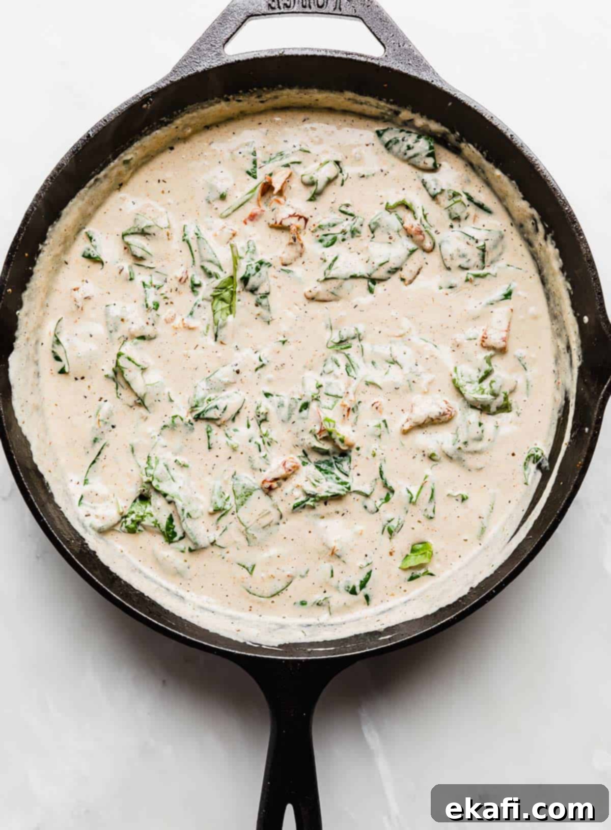 Tuscan Garlic Cream Chicken 6 Creamy Tuscan Chicken gravy with spinach in a cast iron skillet.