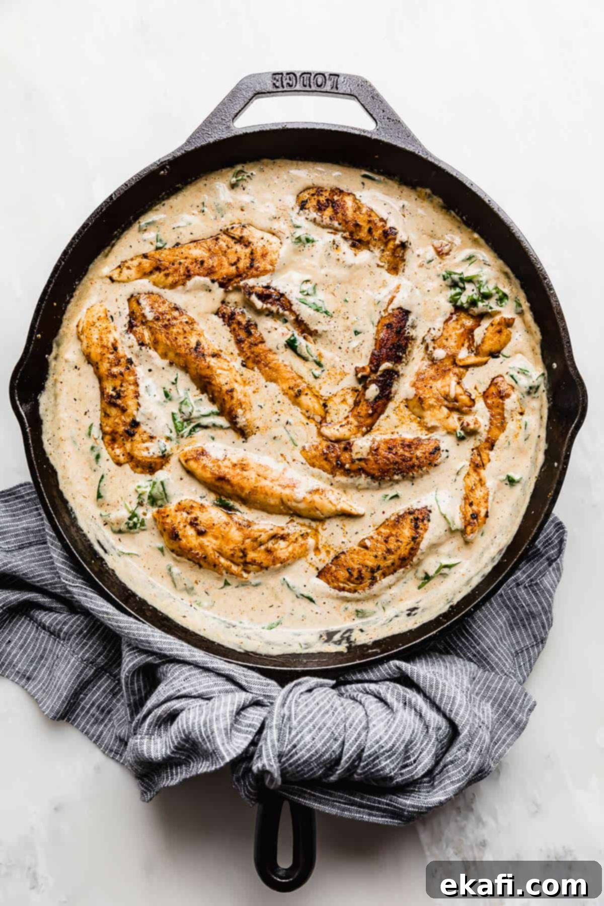 Tuscan Garlic Cream Chicken 7 Creamy Tuscan Chicken Recipe in a skillet on a white background.