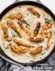 Tuscan Garlic Cream Chicken 9 Creamy Tuscan Chicken in a black skillet with sun dried tomatoes and spinach in the sauce.