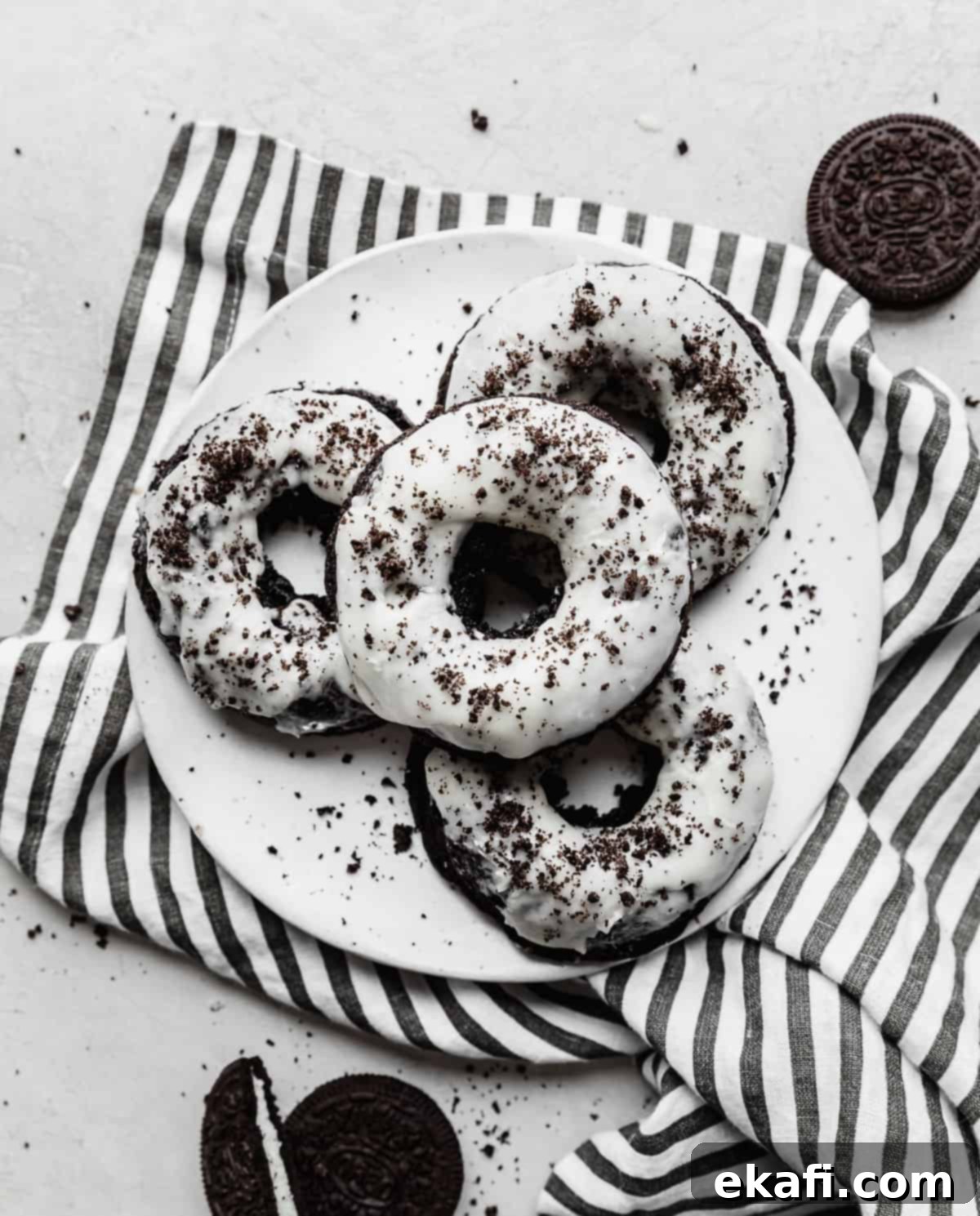 Cookies and Cream Donuts 2 A white plate with four Oreo donuts on it, showcasing their dark color and white frosting.