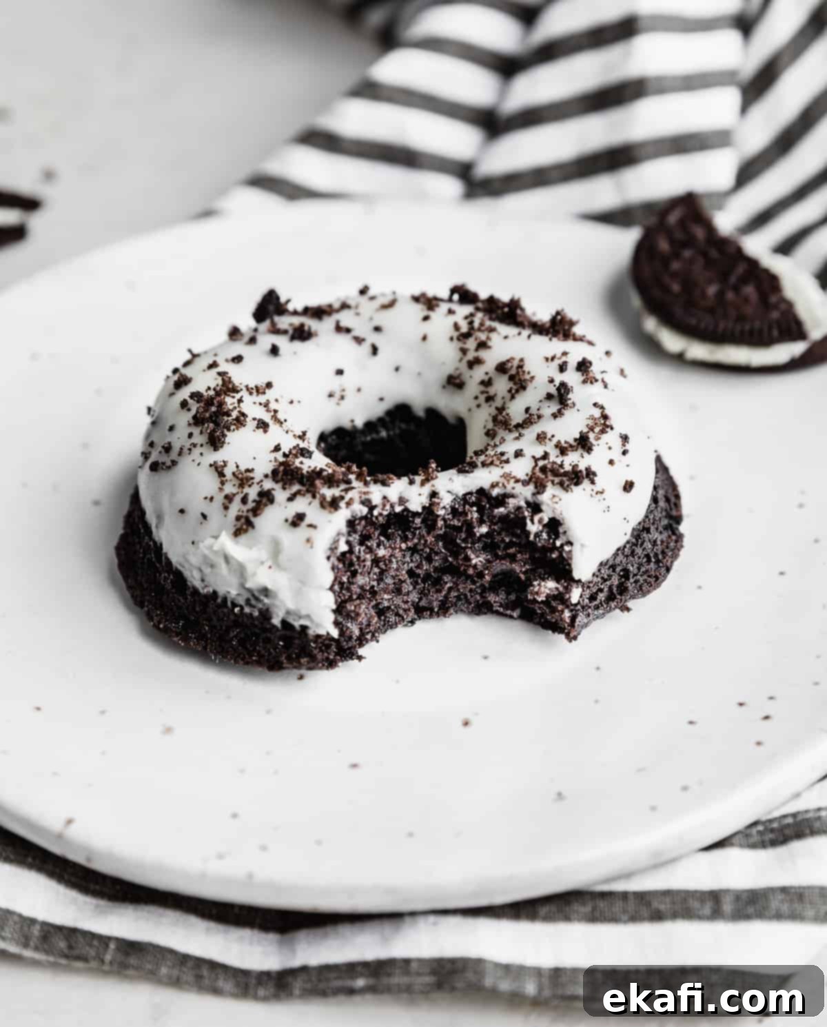Cookies and Cream Donuts 13 An Oreo Donut on a white plate with a bite taken out of it.