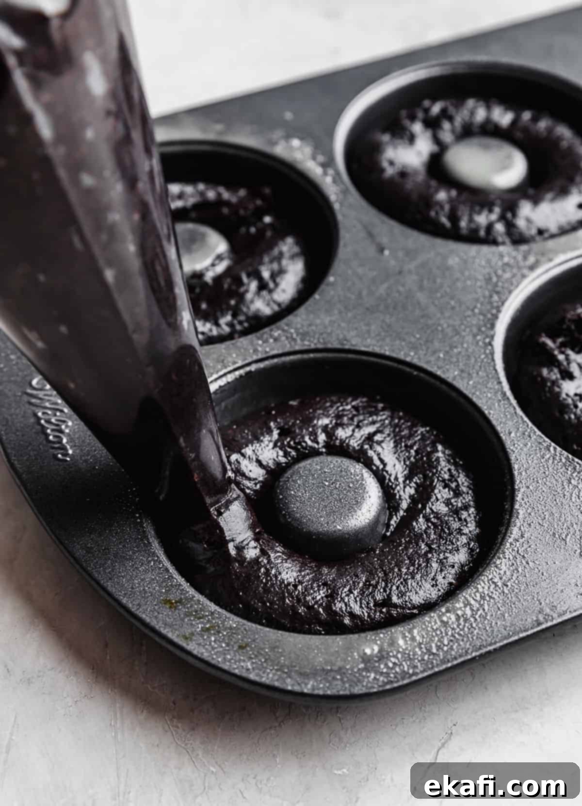 Cookies and Cream Donuts 8 A piping bag piping Oreo Donut batter into a donut pan.