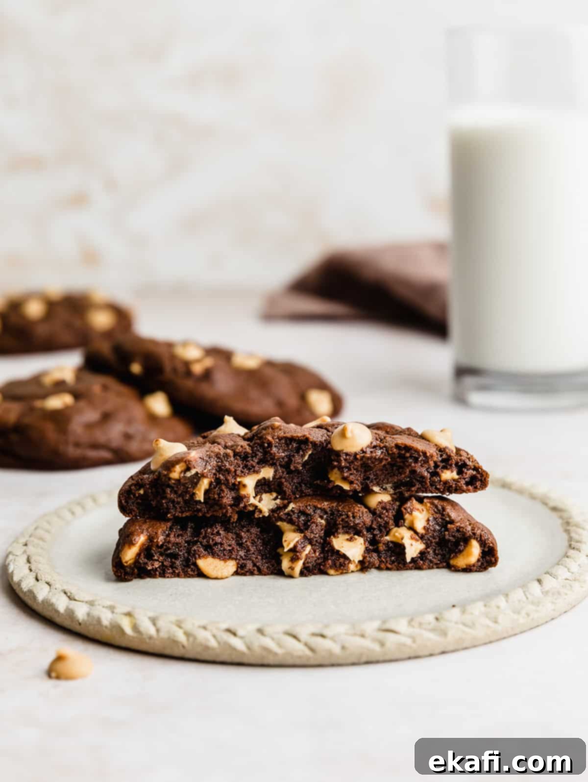 Decadent Peanut Butter Chocolate Chip Cookies 8 A delicious Chocolate Peanut Butter Chip Cookie broken in half, revealing its soft interior and abundant chips, served on a tan plate with a refreshing glass of milk in the background.