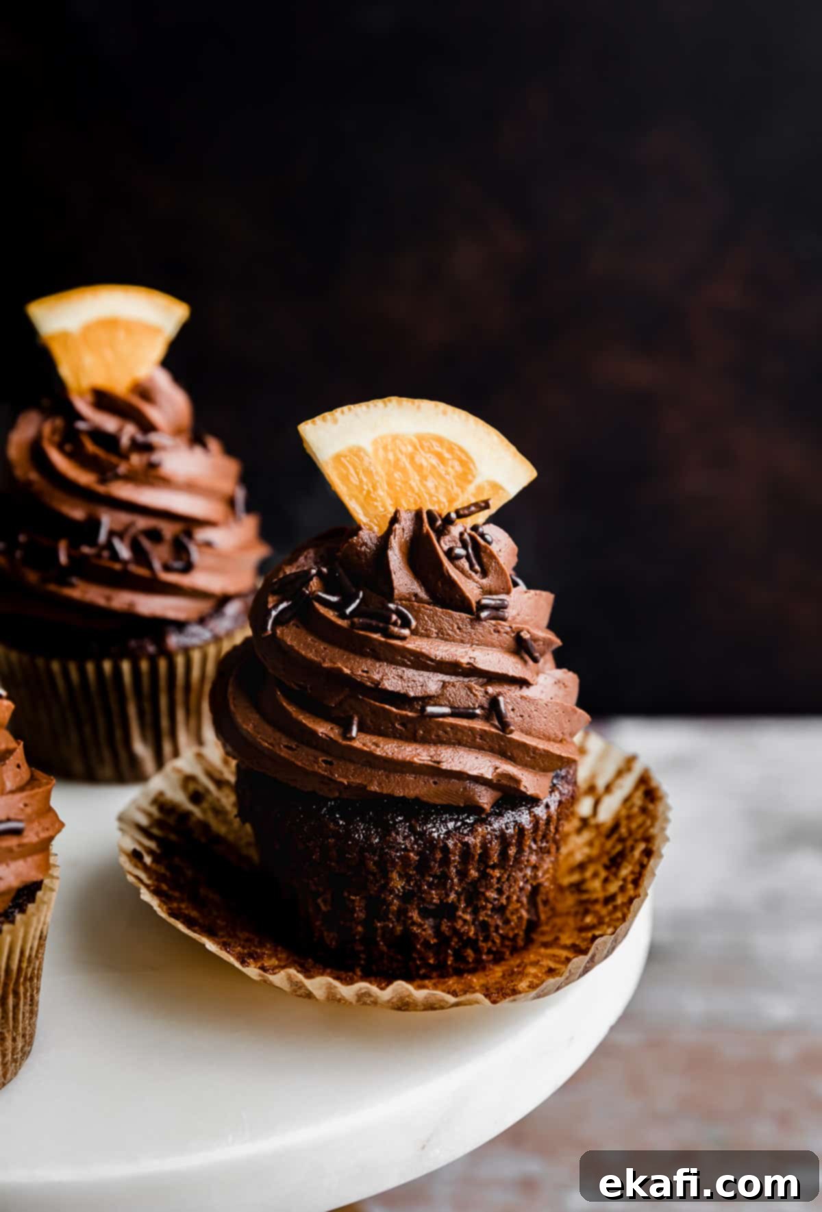 Zesty Chocolate Orange Delights 2 A Chocolate Orange Cupcake with a fresh orange slice on top of the frosting.