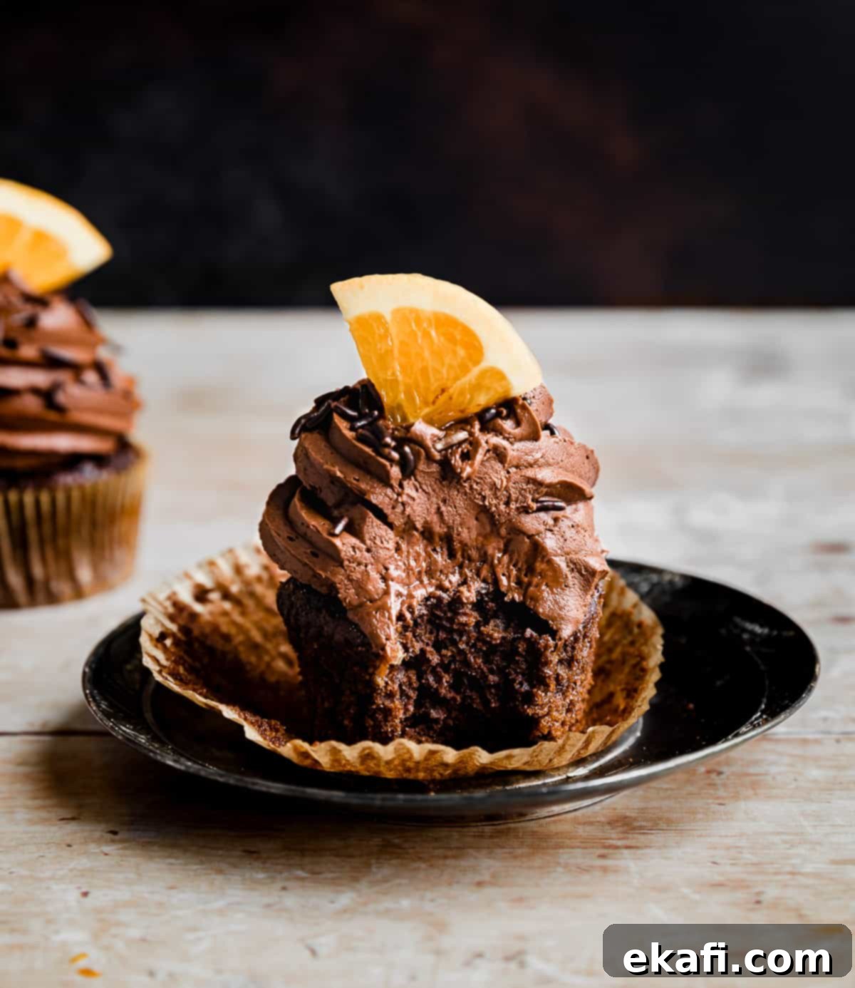 Zesty Chocolate Orange Delights 13 A bite taken out of a fresh orange topped chocolate orange cupcake.