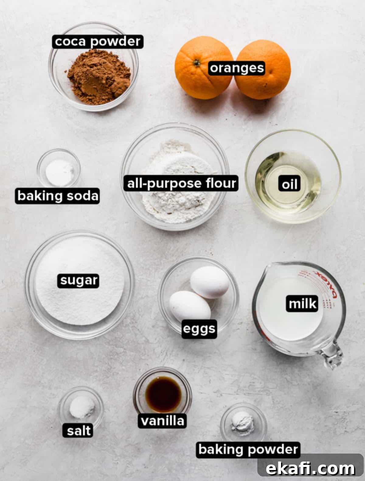 Zesty Chocolate Orange Delights 3 Chocolate Orange Cupcake ingredients in glass bowls on a gray textured background.