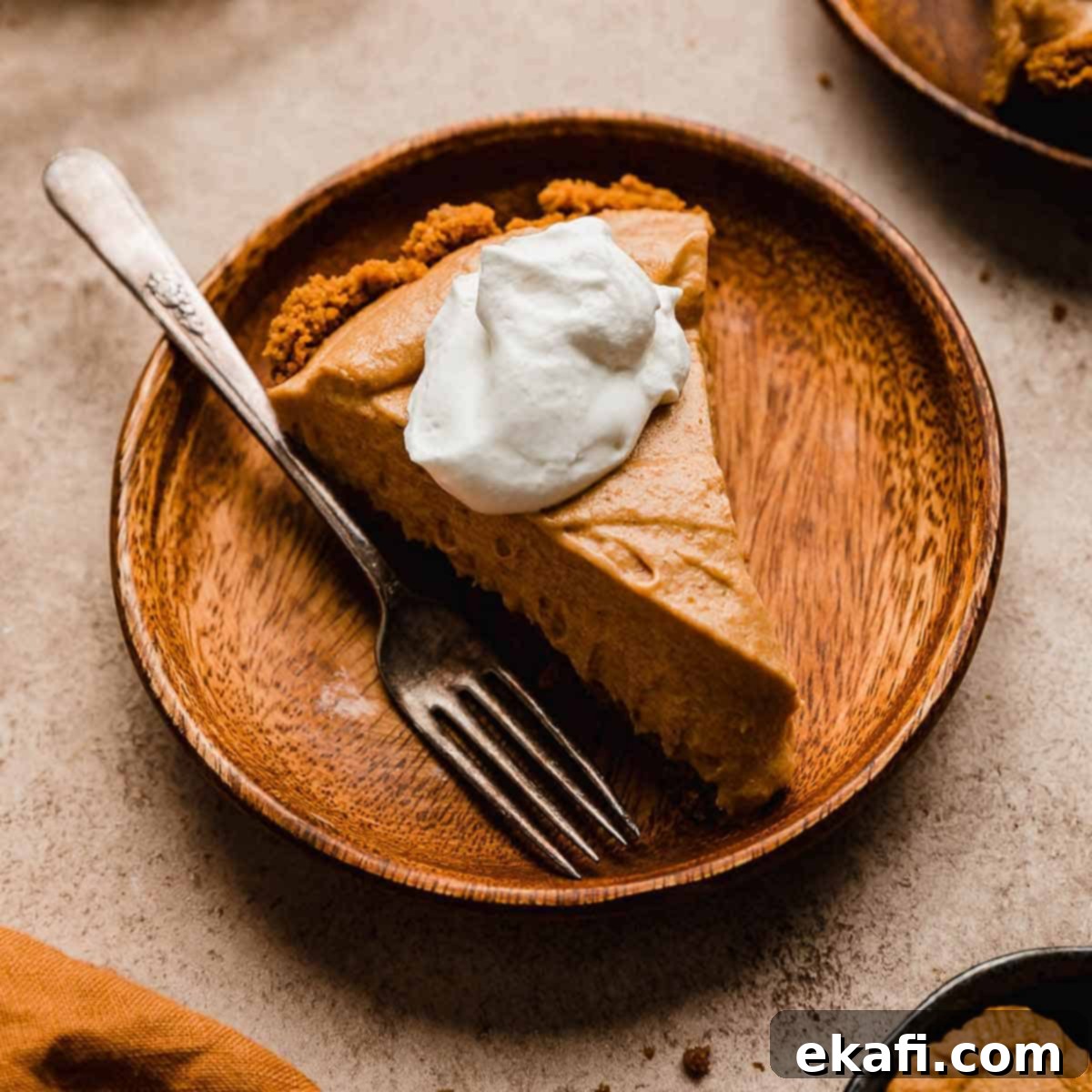 Οι Απόλυτες Πίτες Ευχαριστιών 14 Biscoff Pumpkin Pie με σαντιγί σε ξύλινο πιάτο.