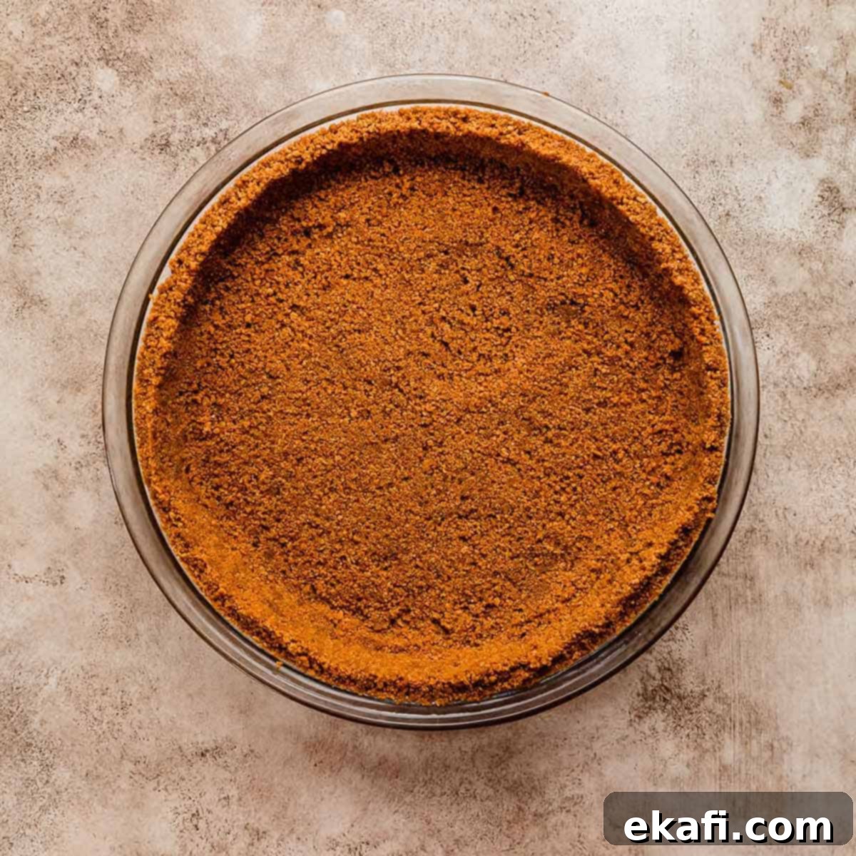Οι Απόλυτες Πίτες Ευχαριστιών 28 Μια κρούστα τάρτας Biscoff σε έντονο πορτοκαλί χρώμα σε μπεζ υφή φόντου.