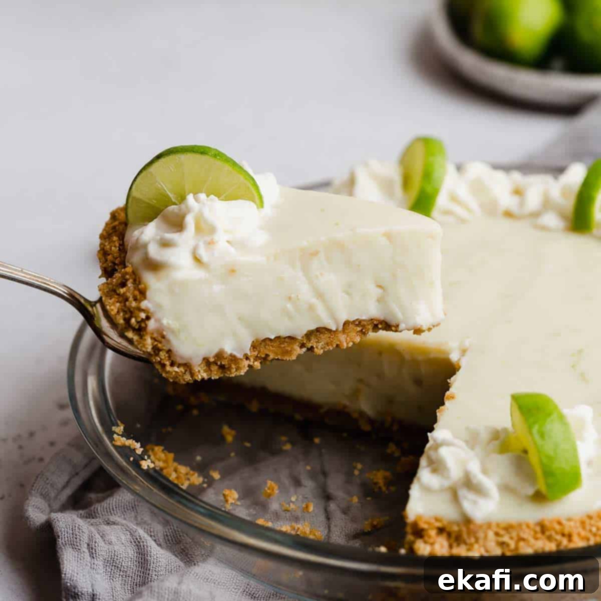 Οι Απόλυτες Πίτες Ευχαριστιών 10 Μια φέτα Key Lime Pie με ξινή κρέμα σε κρούστα από μπισκότα Digestive, ισορροπώντας πάνω σε ένα μαχαίρι σερβιρίσματος.