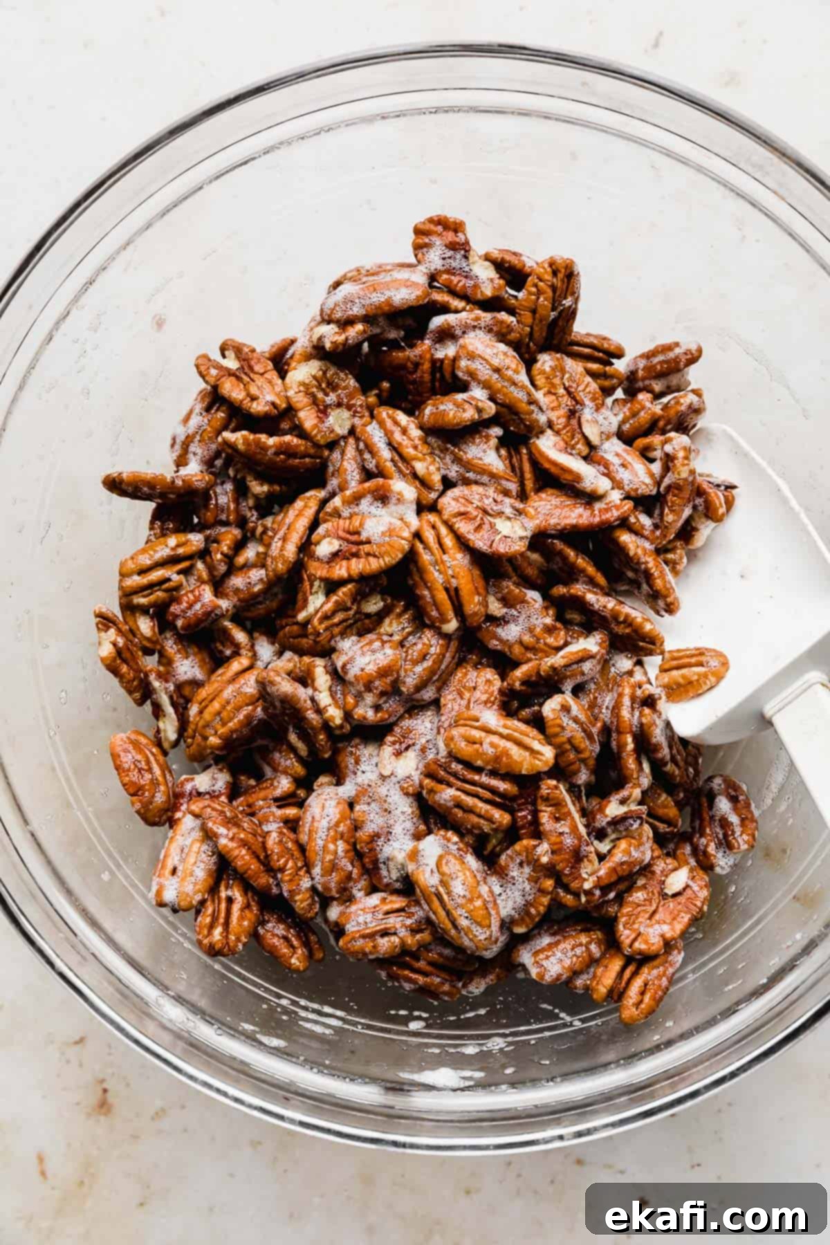 Sweet Glazed Pecans 7 Raw pecans being mixed in frothy egg whites, ensuring each nut is well-coated.