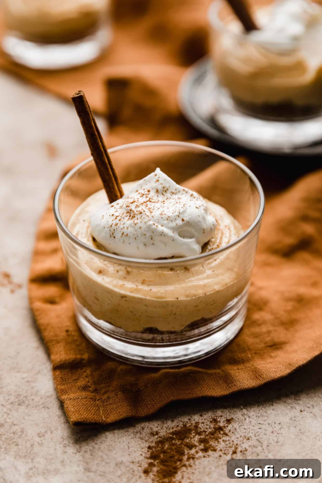 Quick Pumpkin Cheesecake Minis 2 Mini No-Bake Pumpkin Cheesecakes topped with whipped cream in a small glass cup.