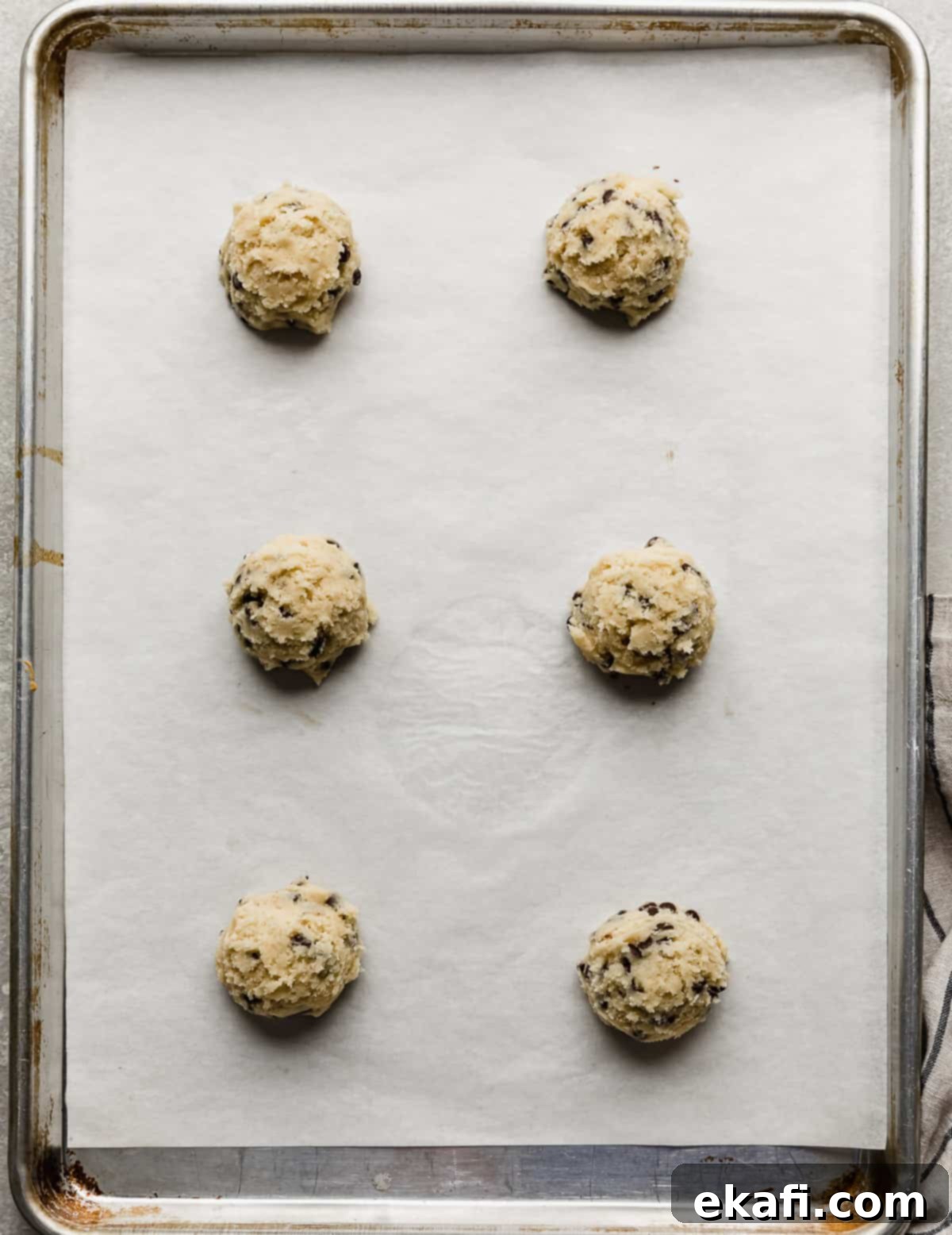 Crumbl's Mint Chip Ice Cream Cookie Delight 7 Six Crumbl Mint Chip Ice Cream Cookie dough balls on a white parchment lined baking sheet.