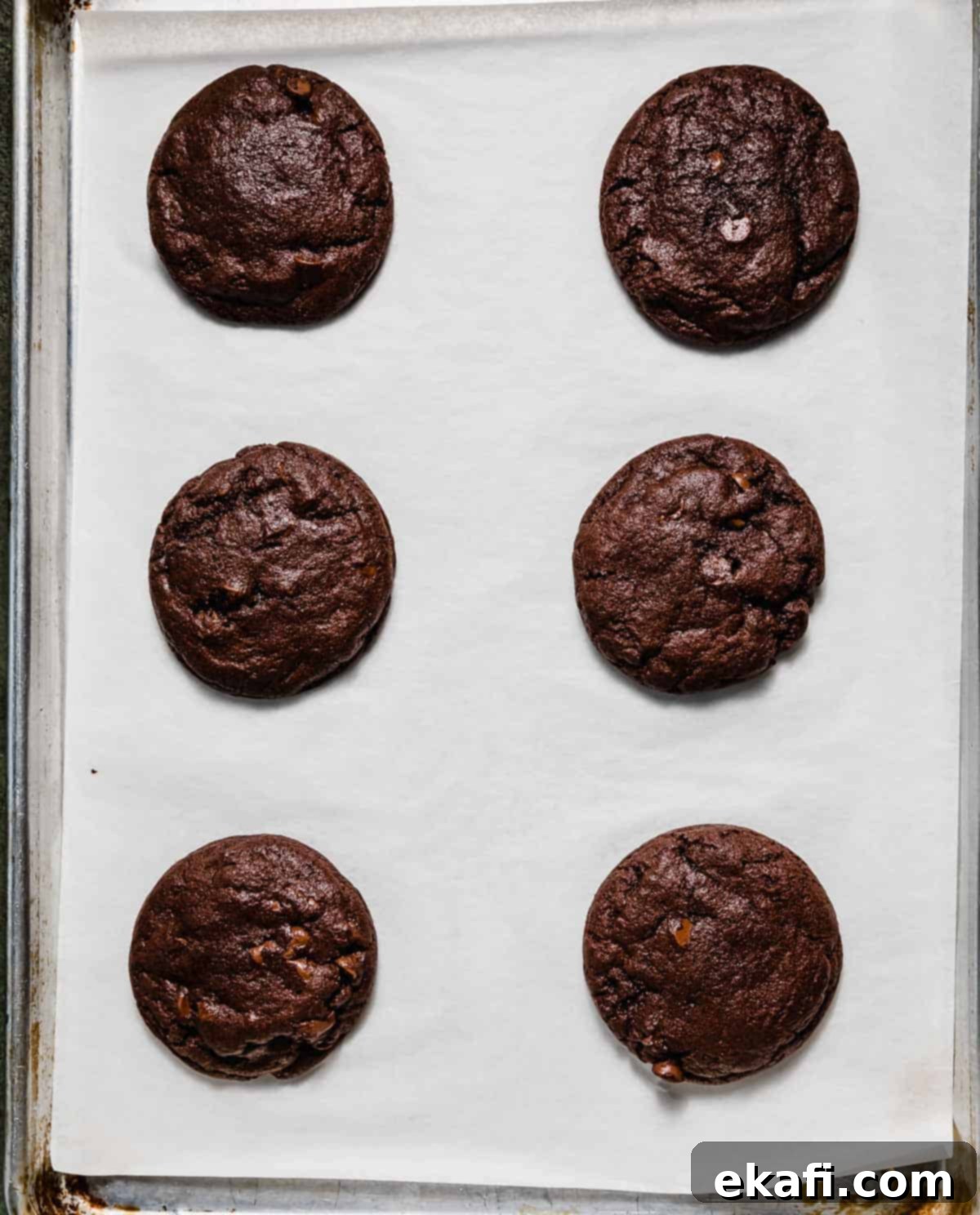 Chocolate Peppermint Bark Cookies 6 Six baked chocolate Peppermint Bark Cookies on a white parchment paper.