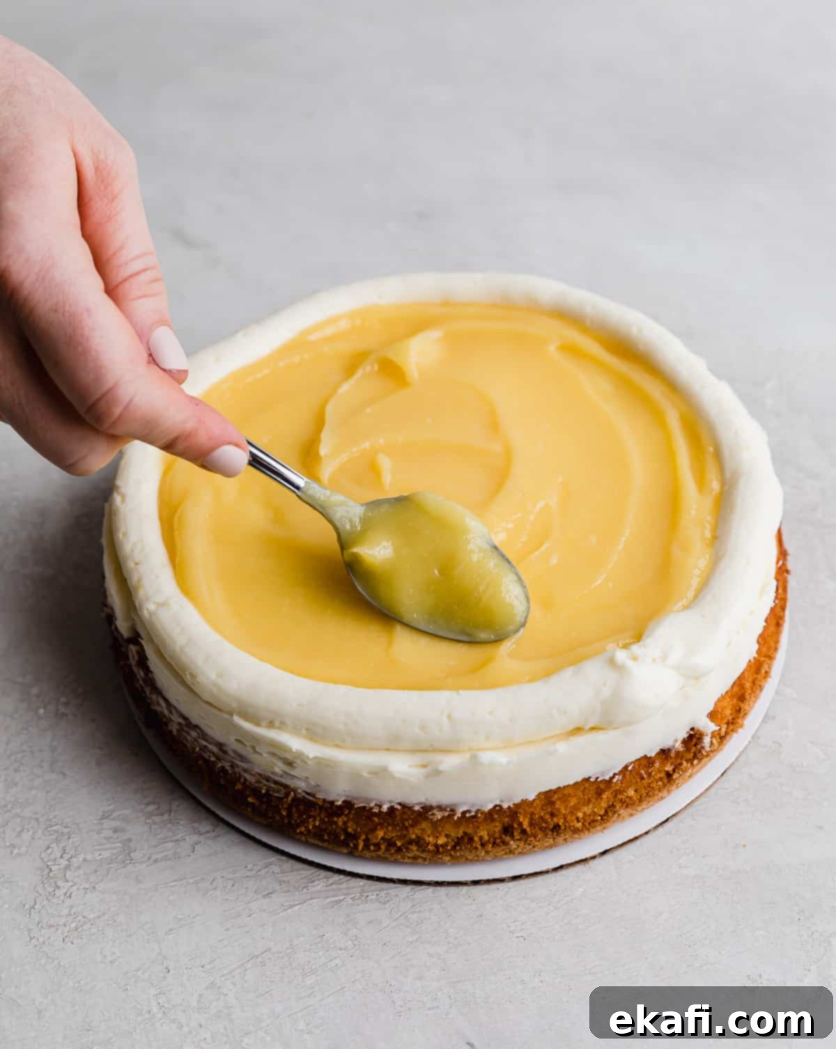 Zesty Lemon Bar Cake 11 A spoon swirling the lemon curd on top of a Lemon Bar Cake.