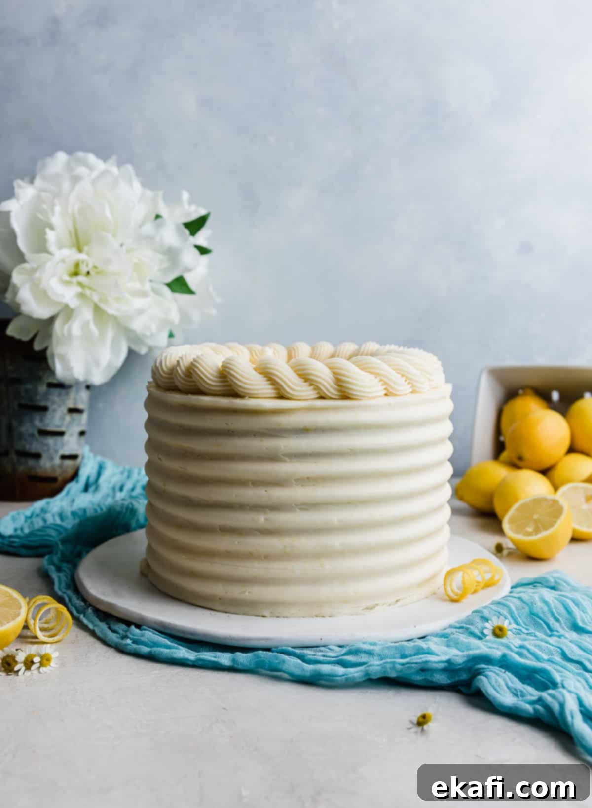 Zesty Lemon Bar Cake 12 A lemon bar cake decorated with textured sides and swirled piping along the top of the cake.