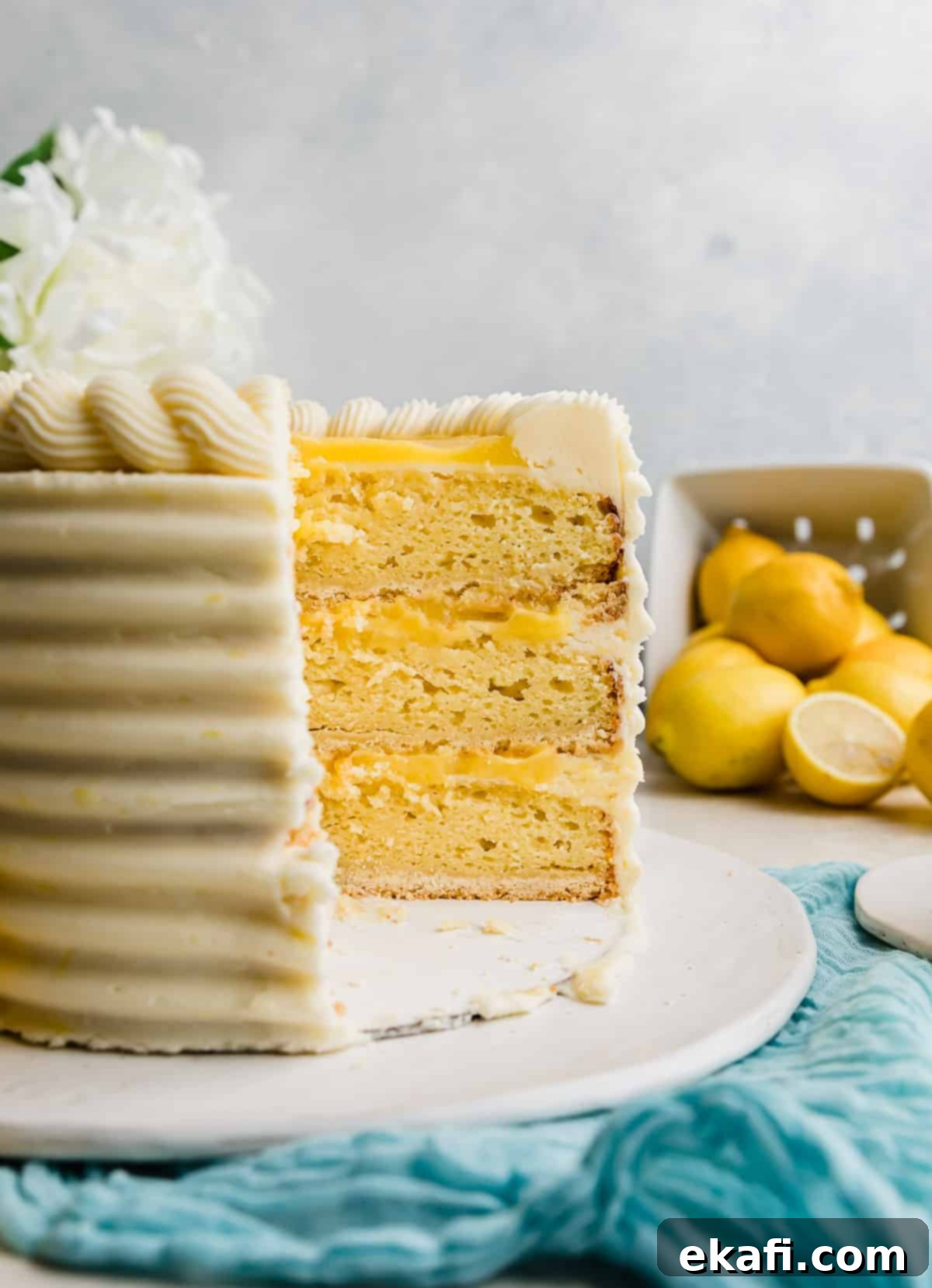 Zesty Lemon Bar Cake 13 A Lemon Bar Cake cut into showing the layers: shortbread crust, lemon cake, lemon curd, and lemon frosting.