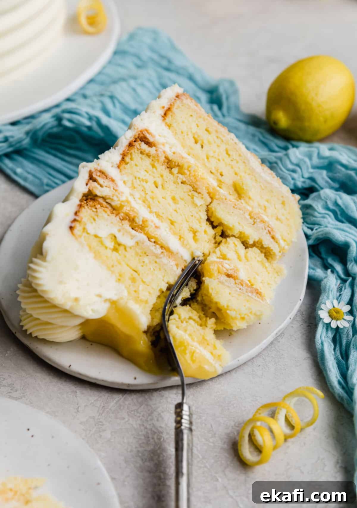 Zesty Lemon Bar Cake 14 A slice of layered Lemon Bar Cake on a plate with a fork cutting into the cake.