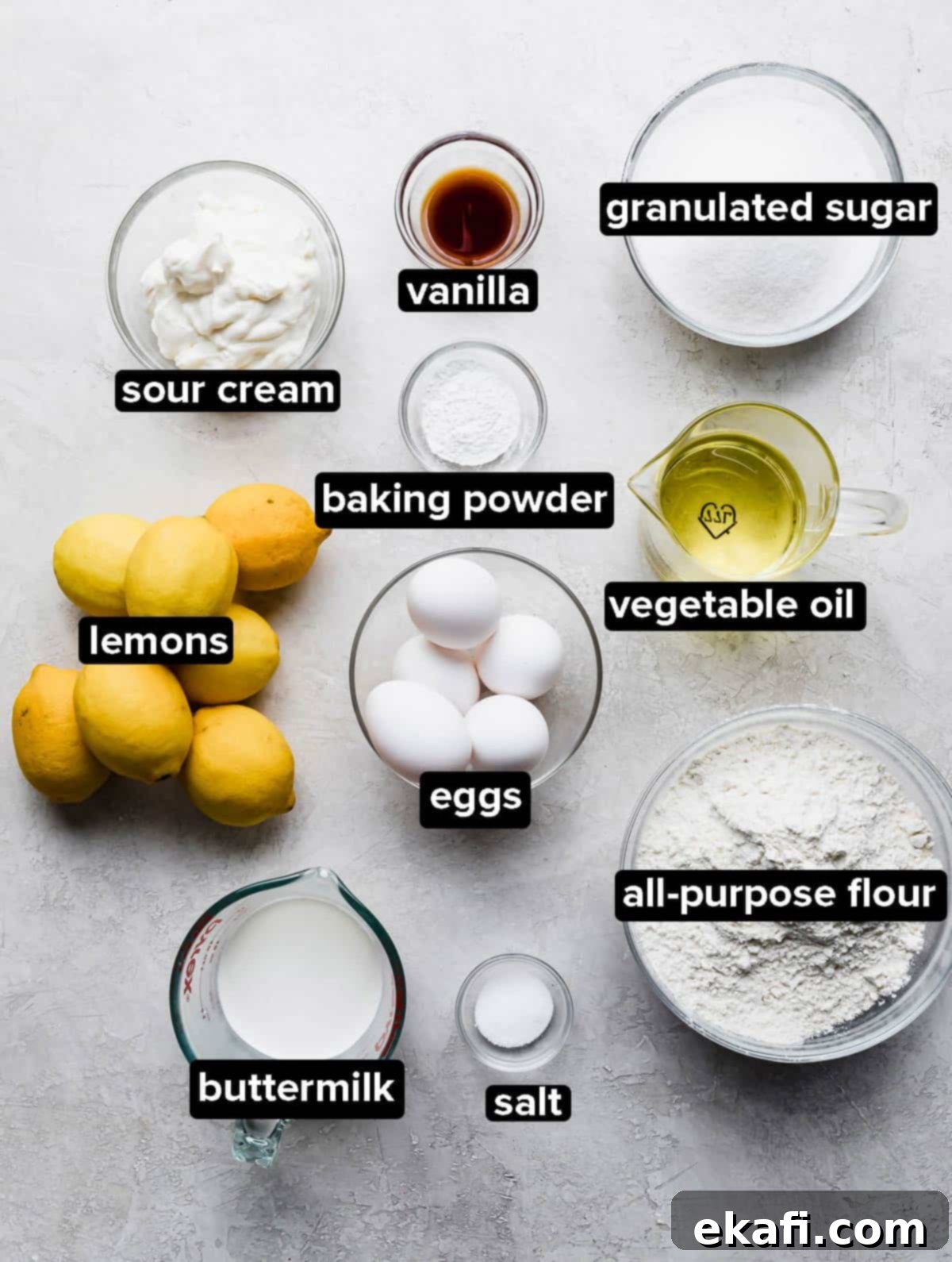 Zesty Lemon Bar Cake 4 Lemon Bar Cake ingredients in glass bowls on a gray background.