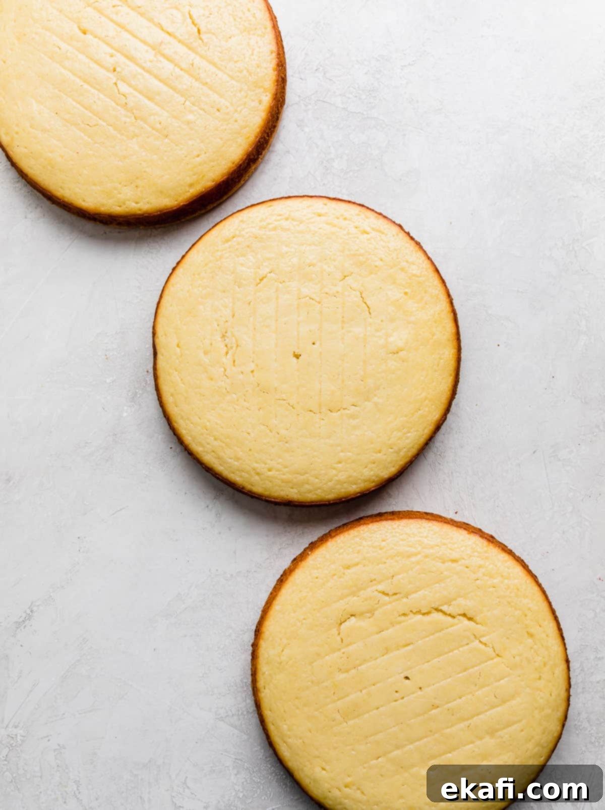 Zesty Lemon Bar Cake 7 Three 8 inch round lemon cakes on a light gray background.