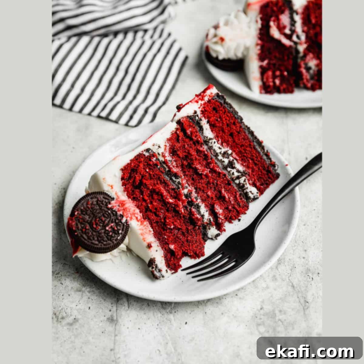 Irresistible Oreo Desserts 5 A slice of Oreo Red Velvet Cake with cream cheese frosting on a white plate on a gray background.